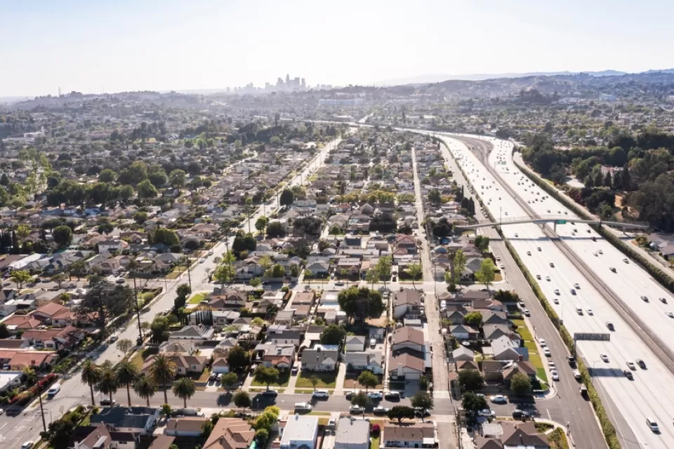 The Interstate 10 freeway cuts through residential neighborhoods in the city of Alhambra. Downtown Los Angeles is visible in the background,